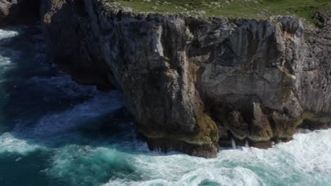 Cavern-of-bufones-de-pria-asturias-spain-sheer-drop-off-sea-cliffs-bombarded-by-waves,-slow-motion