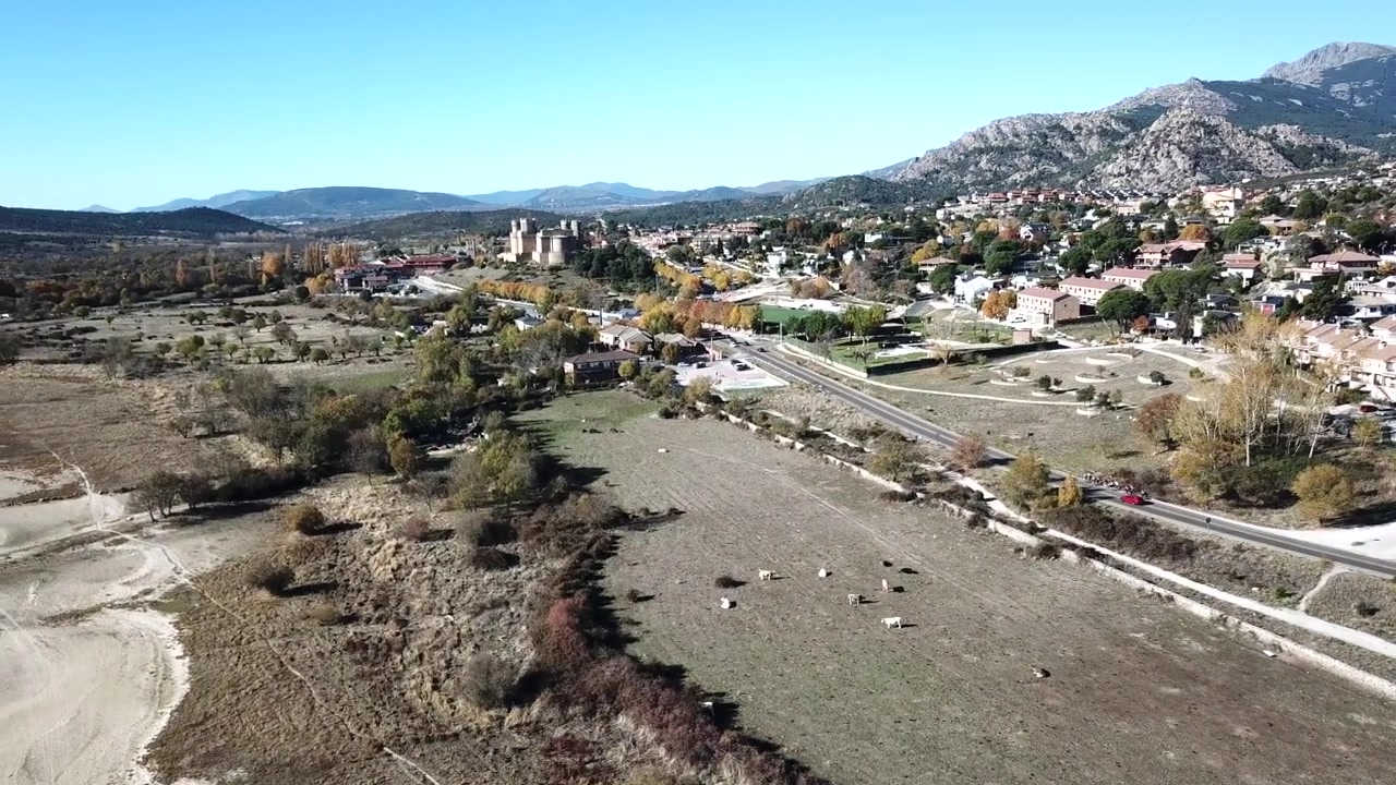 Filmato aereo del villaggio di Manzanares el Real e del castello medievale nella regione di Madrid, Spagna. Il castello storico si erge contro le montagne della Sierra de Guadarrama con il bacino di Santillana.