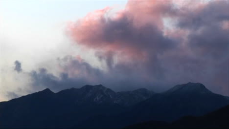 nubes oscuras ruedan sobre montañas bajas cerca del atardecer