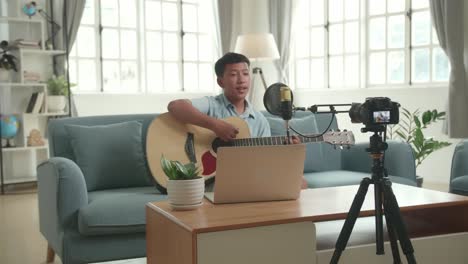 young musician recording a guitar song at home