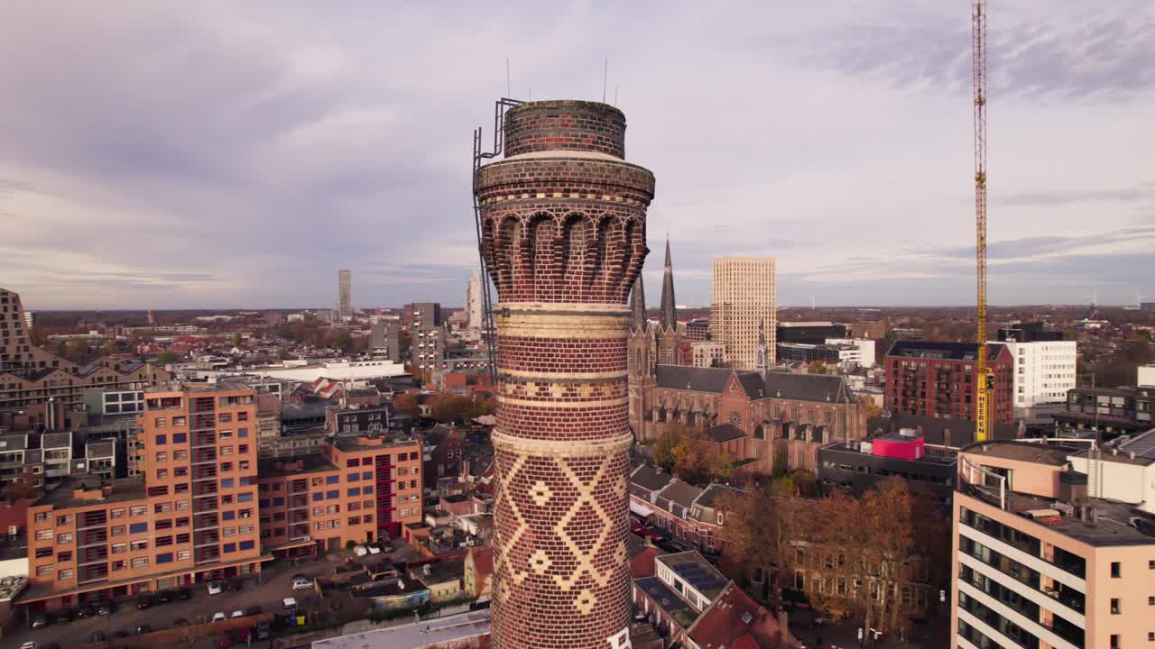 Luftaufnahme von der Spitze des Schornsteins, die um das Industriegebäude Kazernehof schwenkt, mit breiteren Gewerbe- und Unterhaltungsstätten im Hintergrund