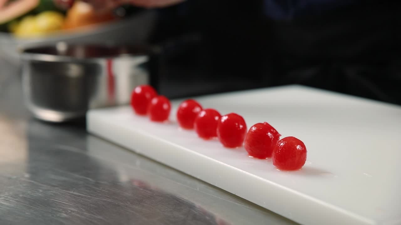 요리사 가 절단판 에 체리를 배열 하고 있다