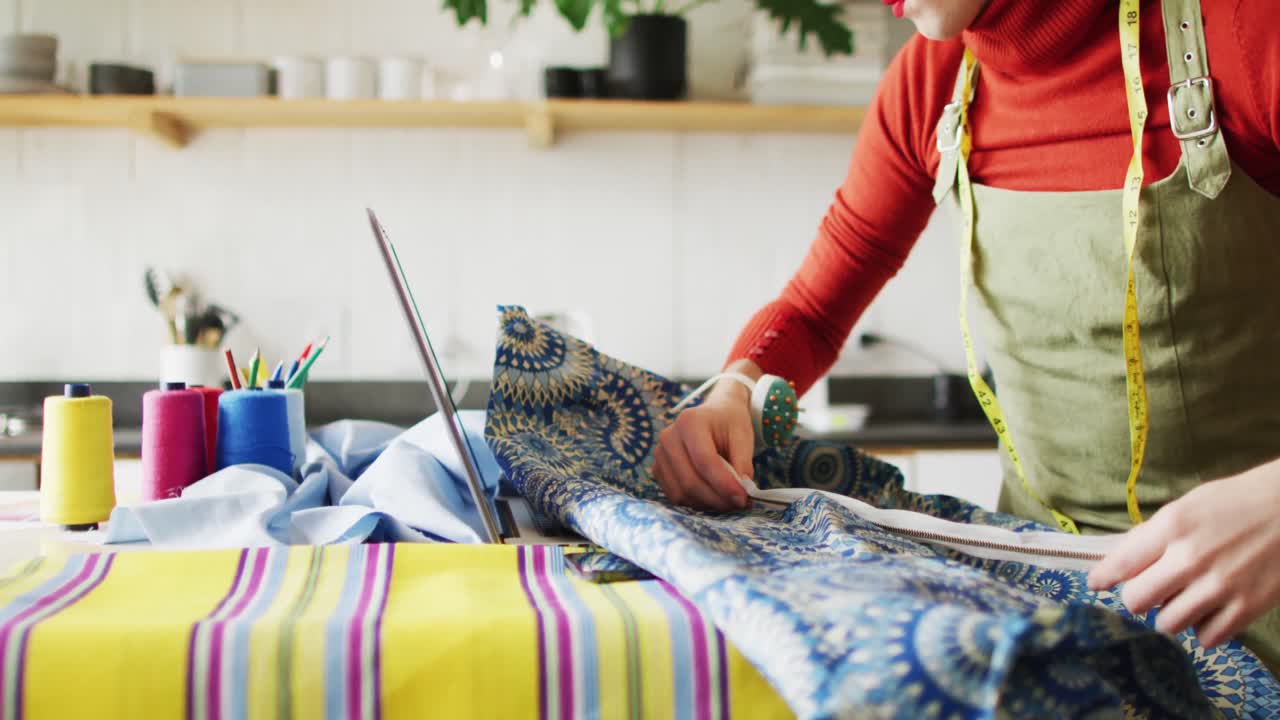 mujer transgénero caucásica no binaria que trabaja en casa, cosiendo