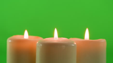 three burning candles on a green background