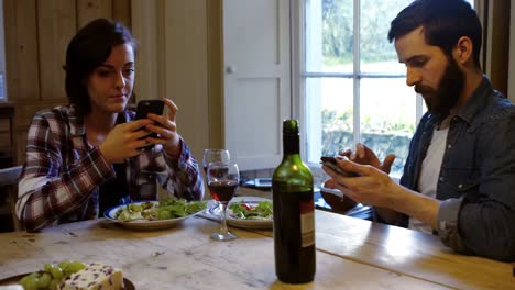 couple using mobile phone while having meal