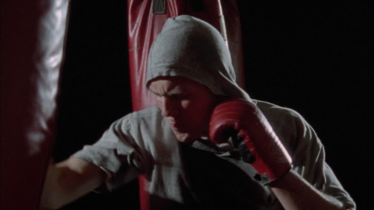 重いバッグを殴りながら踊る男