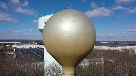 an aerial shot orbiting a silver water tower with another blue one in the background