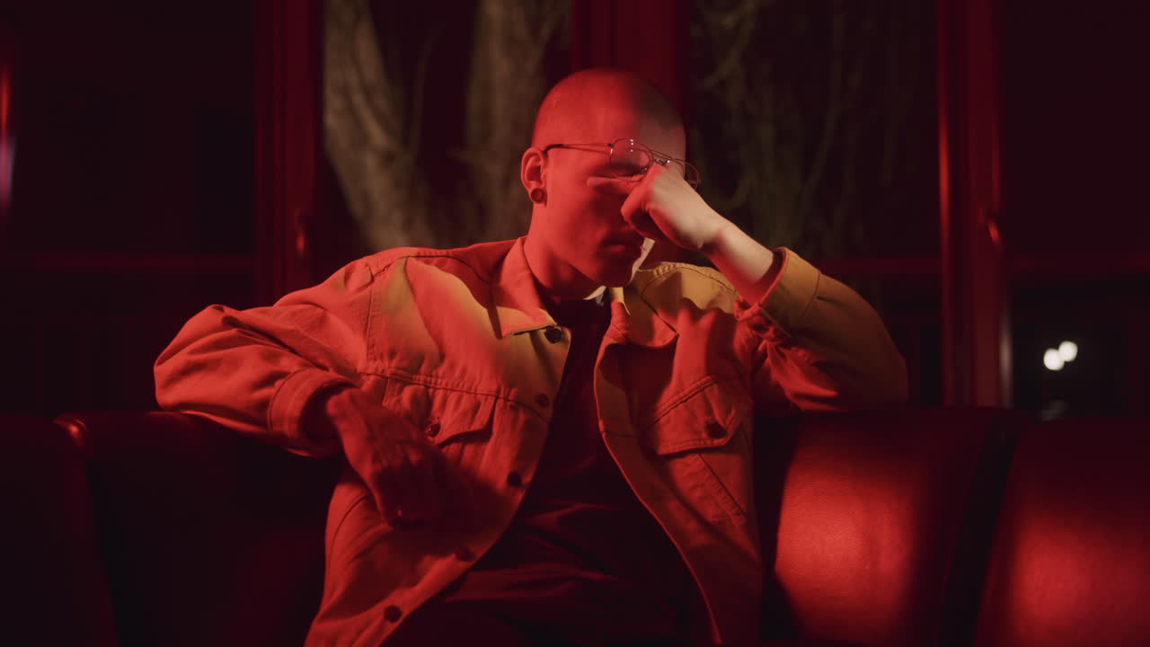 Man Sitting on a Couch in a Red-Lit Room