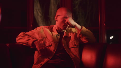 man sitting on a couch in a red-lit room