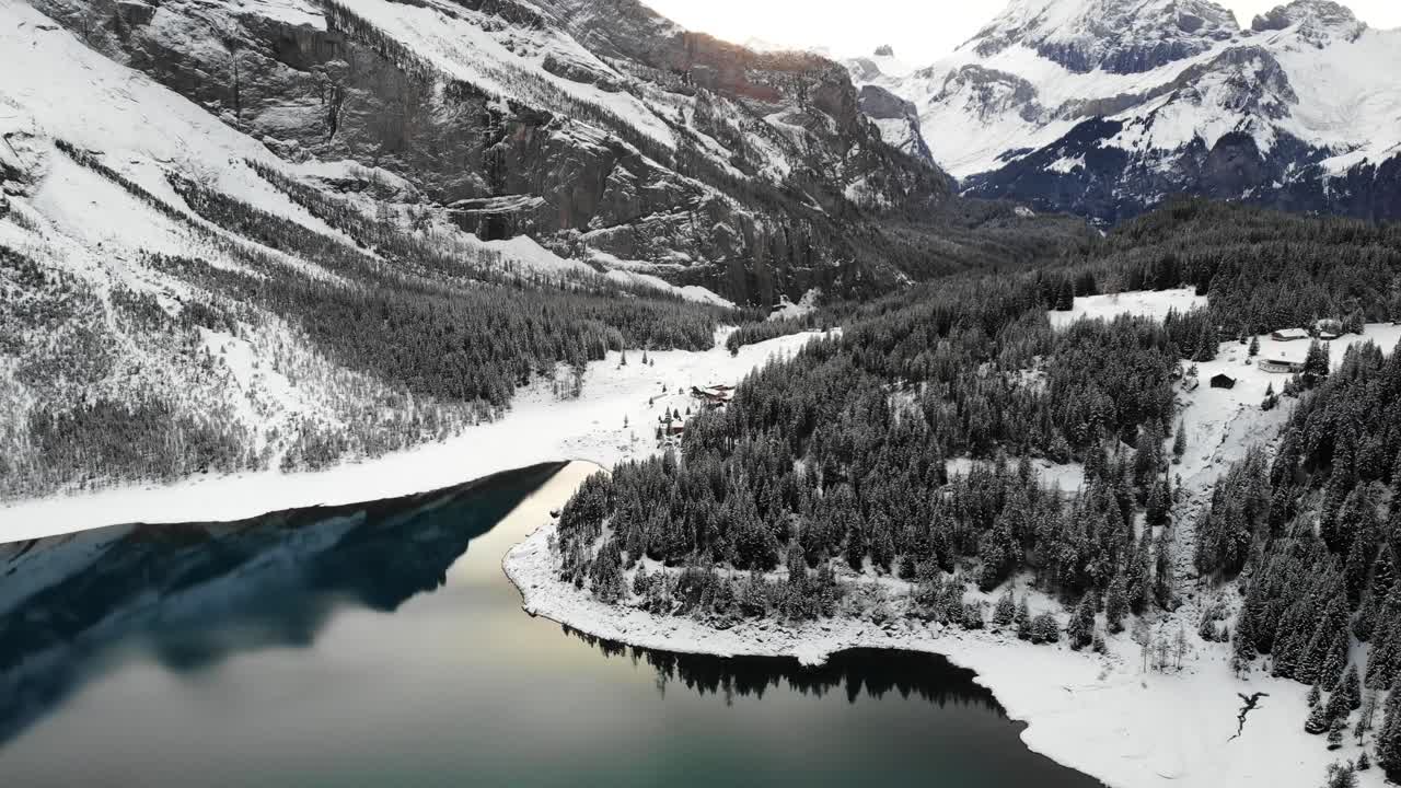 Sorvolo aereo sulle rive del lago Oeschinensee a Kandersteg, Svizzera, in una fredda giornata invernale con alberi coperti di neve