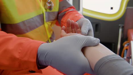 vista de cerca de un paramédico tocando la mano de un paciente acostado en una camilla dentro de una ambulancia