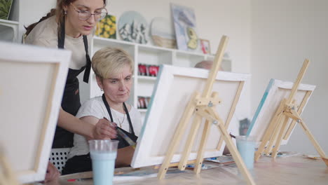 an old retired woman paints a picture together with friends. an elderly group of friends and a senior woman are drawing pictures together.