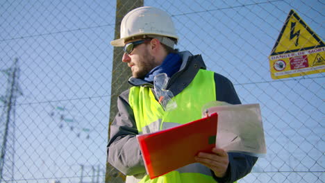 Männlicher-Ingenieur-Hält-Klemmbrett-In-Der-Hand-Und-Diktiert-Anweisungen,-Während-Er-Richtungen-Zeigt,-Handheld-Dynamik