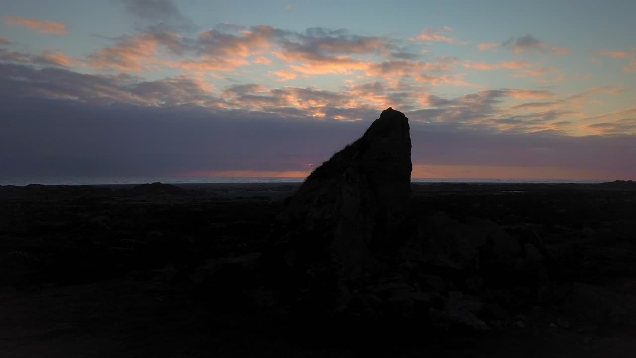 vista aérea de una silueta de roca al atardecer en la playa de whatipu, nueva zelanda
