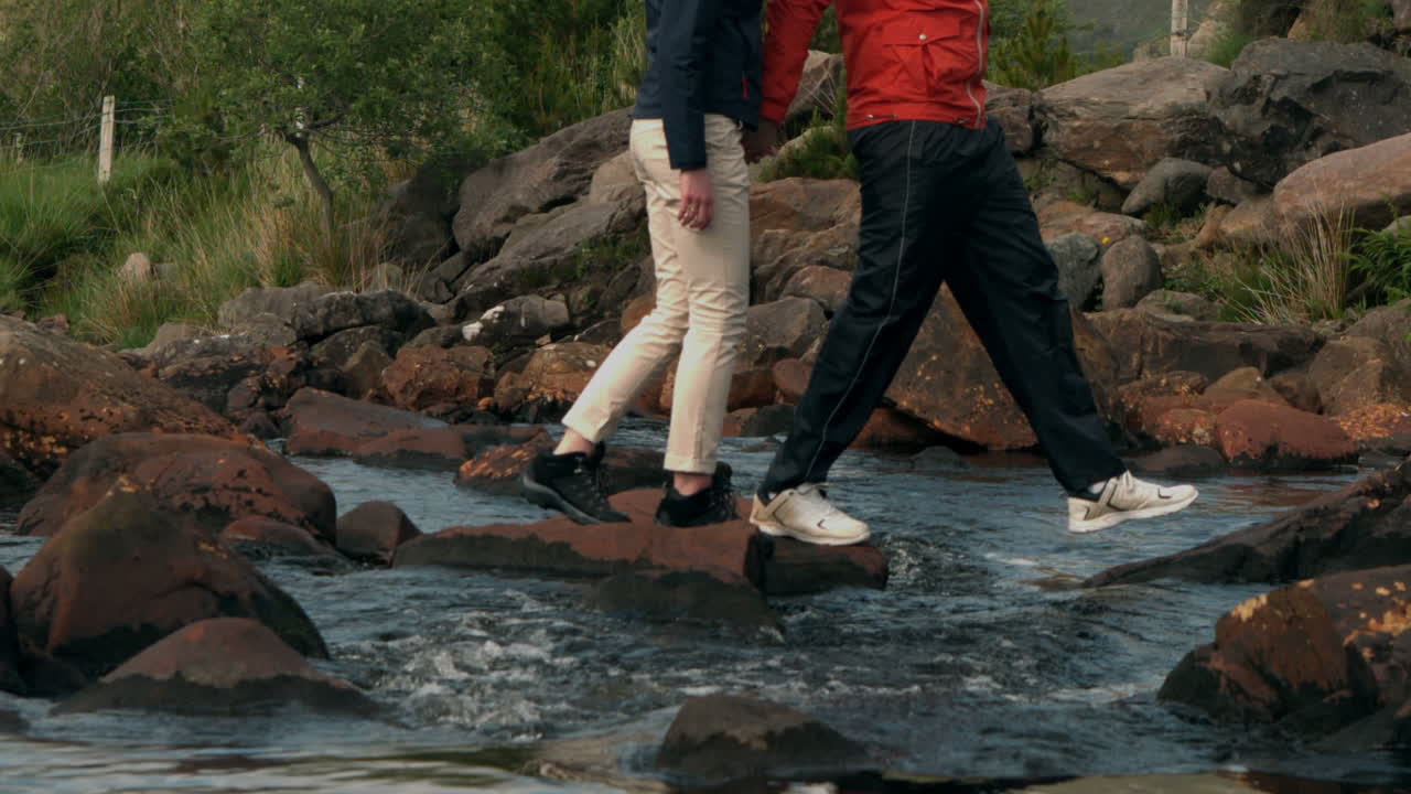 pareja cruzando un arroyo juntos en el campo