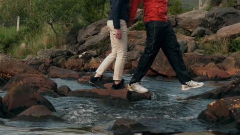 Couple-crossing-a-stream-together-in-the-countryside