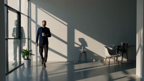 businessman walking in modern office with coffee