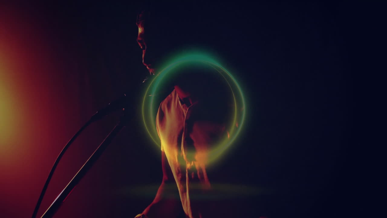 Male singer singing into microphone in music tech studio, with neon green-yellow light ring overlay