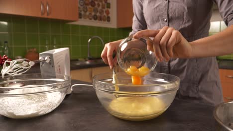 a close-up shot of a young woman adding yolk into a honey butter mixture and using an electric mixer to mix them together