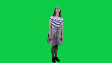 side view teenage girl vibing to music in front of a green screen