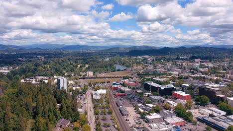 drone flying above city of eugene in oregon with view of willamette river on a bright sunny day - aerial