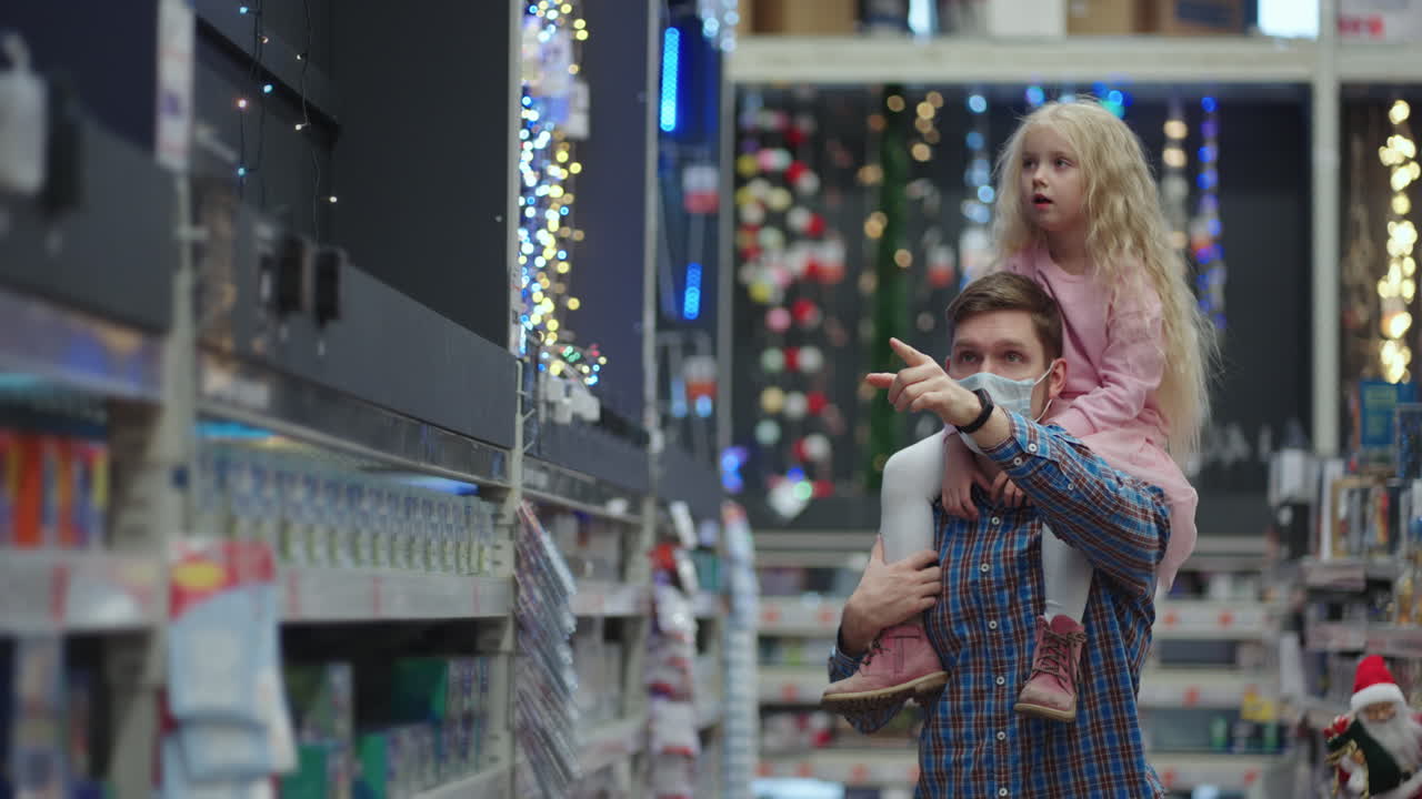 아빠와 딸은 크리스마스 트리용 장난감과 가게의 집에서 장식과 화환을 선택합니다. 크리스마스 화환과 장식