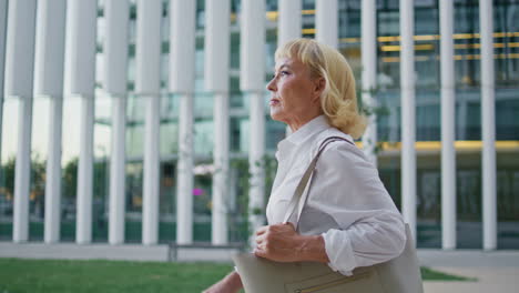 hermosa anciana paseando por el distrito urbano de primer plano. mujer de negocios jubilada yendo