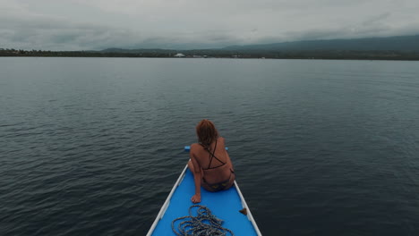 Cinematic-shot-of-a-beautiful-girl-in-a-bikini-on-an-outrigger-boat-with-a-stormy-scene-in-the-background,-Philippines,-Asia