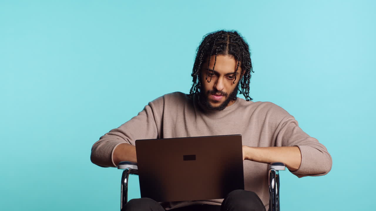 Man composing email, typing on laptop keyboard, studio background