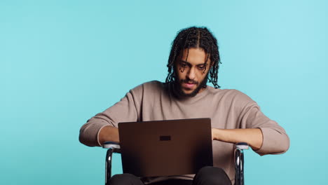 man composing email, typing on laptop keyboard, studio background