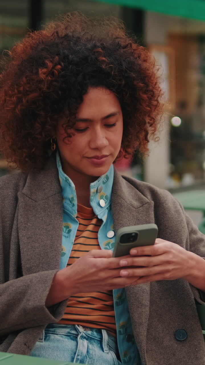 Young Woman Using Smartphone at Outdoor Cafe
