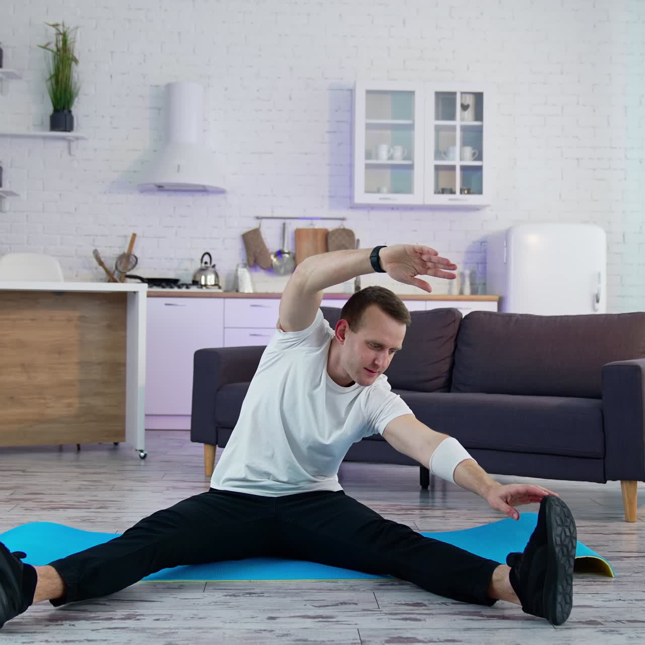 Caucasian during workout at home. Young man doing slopes and exercising in living room at home during the quarantine
