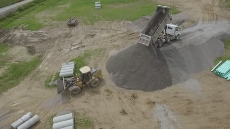 aerial of dump truck unloading gravel off a inclined gravel ramp