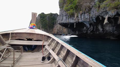 Ein-Longtail-Boot-Verlässt-Die-Bucht-Von-Koh-Phi-Phi-Leh-Island-Mit-Kalksteinfelsen-Und-Türkisfarbenem-Wasser-In-Krabi,-Thailand