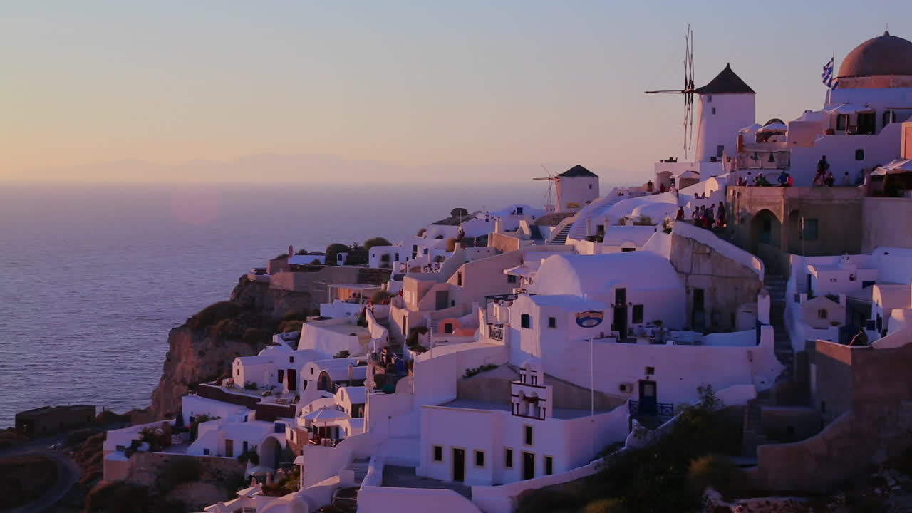 edificios blancos y molinos de viento bordean las laderas de la isla griega de santorini al atardecer 2