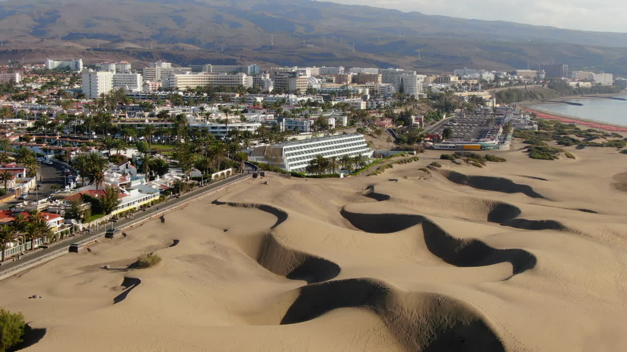 Stunning aerial perspective of the iconic sand dunes bordering the vibrant cityscape of Maspalomas
