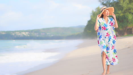 Elegante-Mujer-Exótica-Con-Un-Colorido-Vestido-De-Verano-Caminando-En-La-Playa-De-Arena-Junto-Al-Mar-Tropical-Levantando-Las-Manos-Llenas-De-Alegría,-Cámara-Lenta-De-Marco-Completo