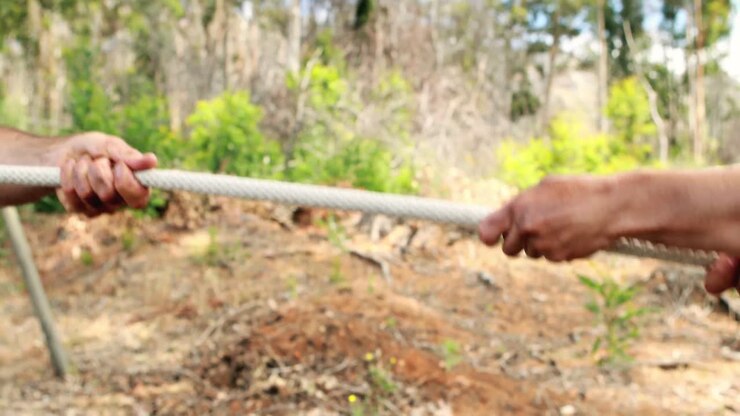 Fit man and woman playing tug of war during obstacle course