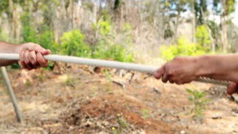 Fit-man-and-woman-playing-tug-of-war-during-obstacle-course