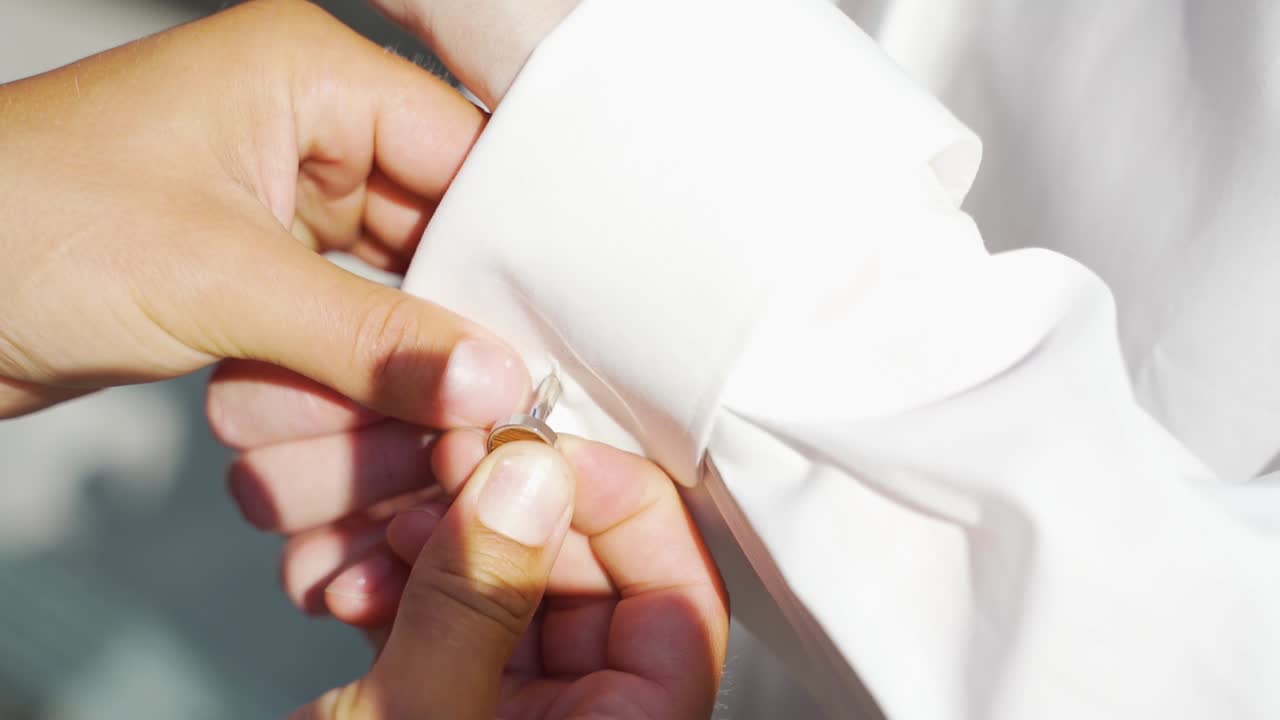 Helping Hand Putting On Cufflinks On White Shirt Off Groom. Close Up, Follow Shot