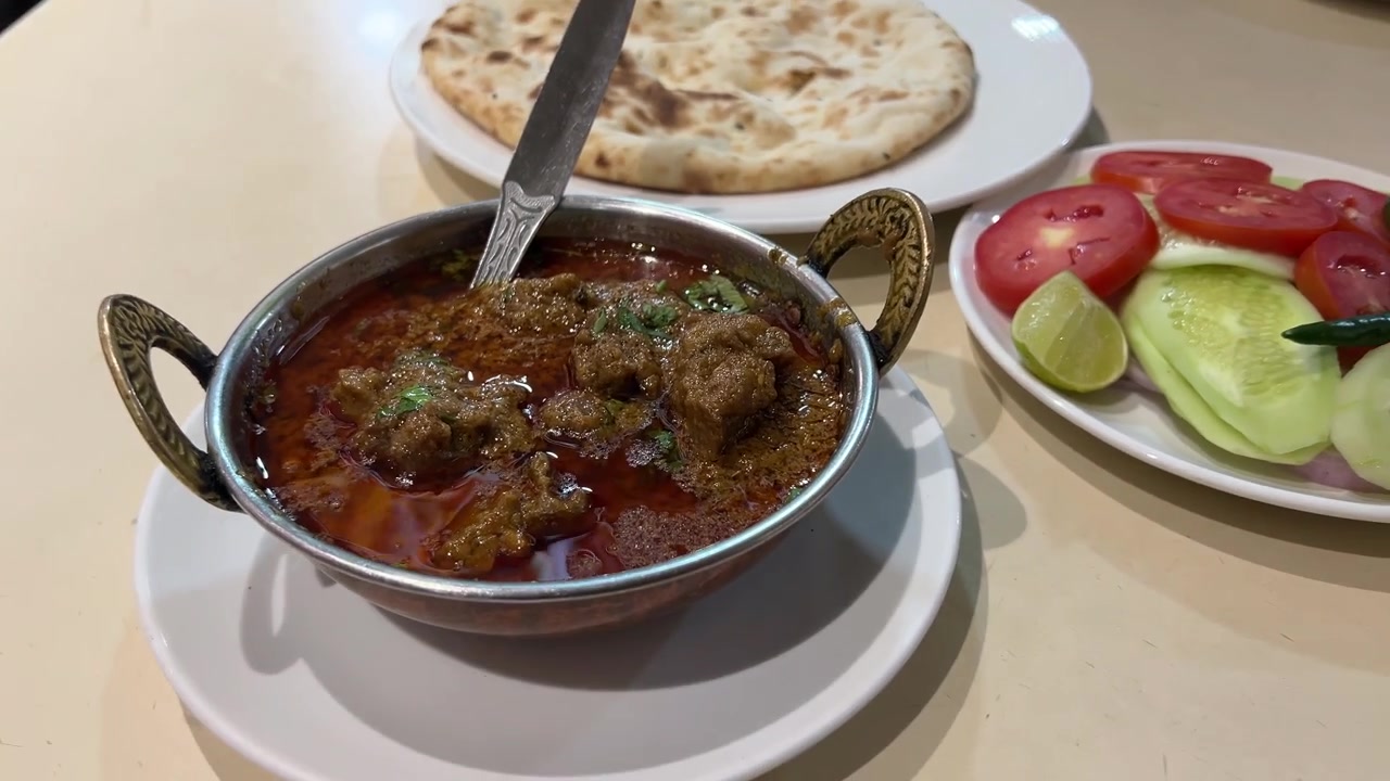 Piatto di curry di montone e khameri roti servito con insalata in un ristorante indiano