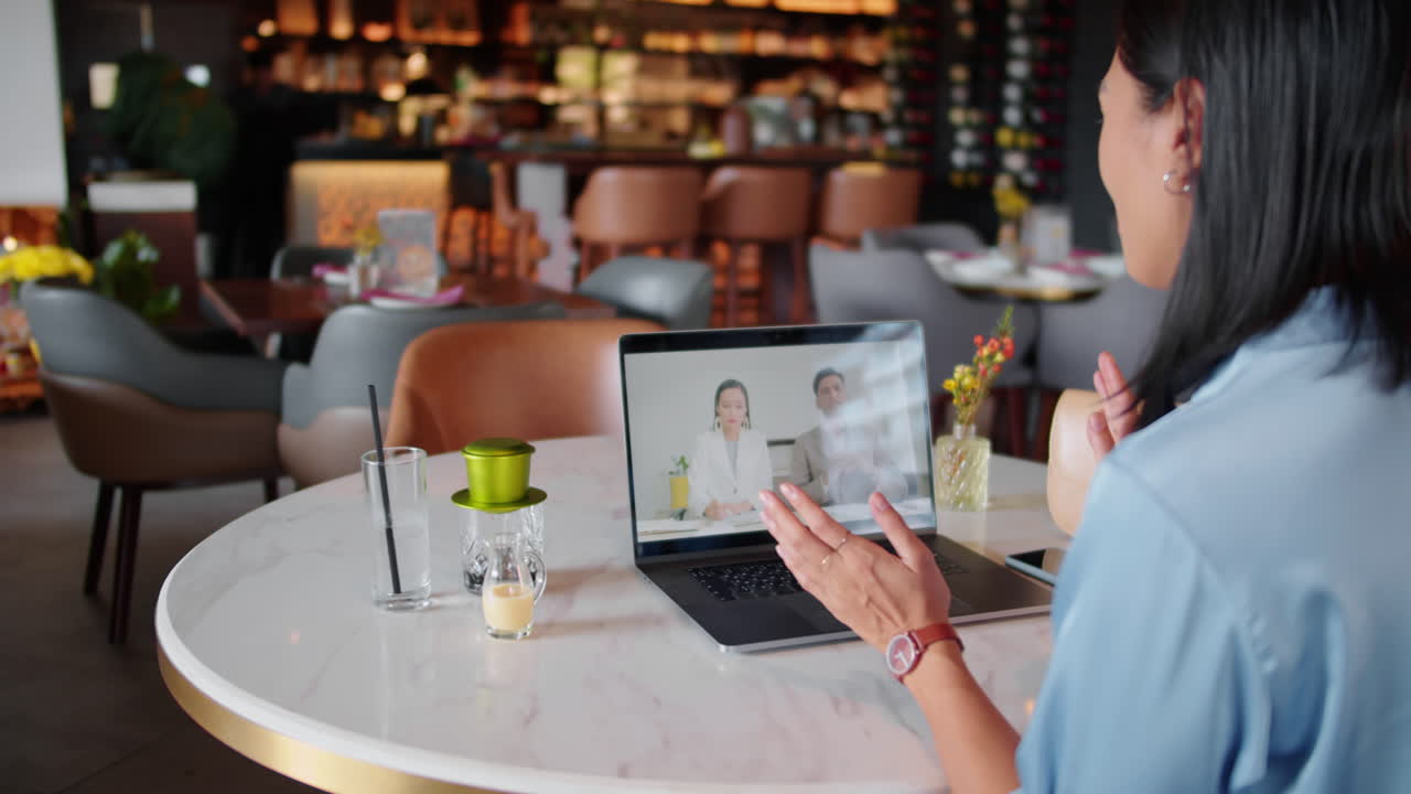 Consultora de marketing atendendo clientes por videochamada em um laptop em um café
