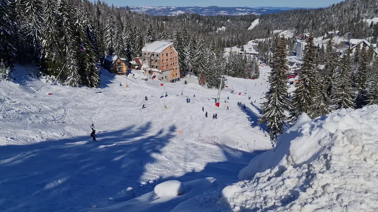 Lidé lyžující a snowboardující na zasněžené sjezdovce v zimním lyžařském středisku