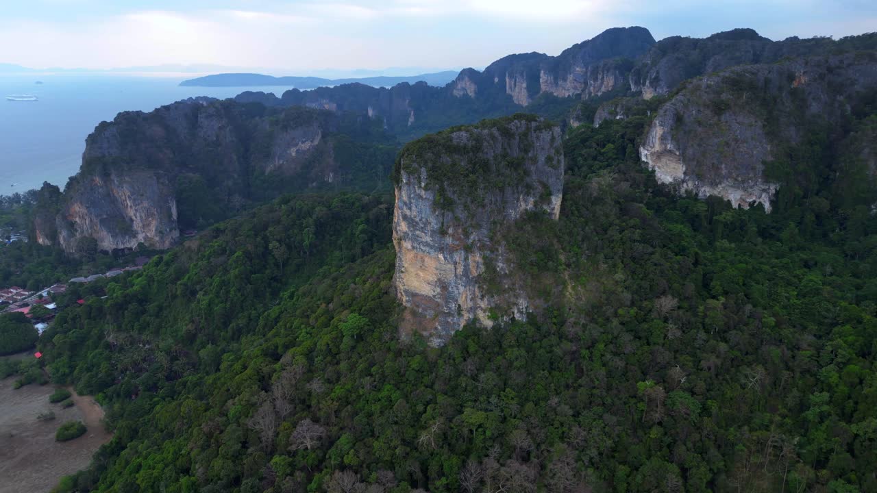 Rai Leh beach towering limestone cliffs emerging from tropical forest in Krabi, Thailand. Amazing aerial view flight wide orbit overview drone