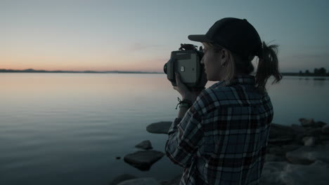 Frau-Filmt-Den-Sonnenuntergang-über-Dem-See-Mit-Einer-Vintage-Videokamera