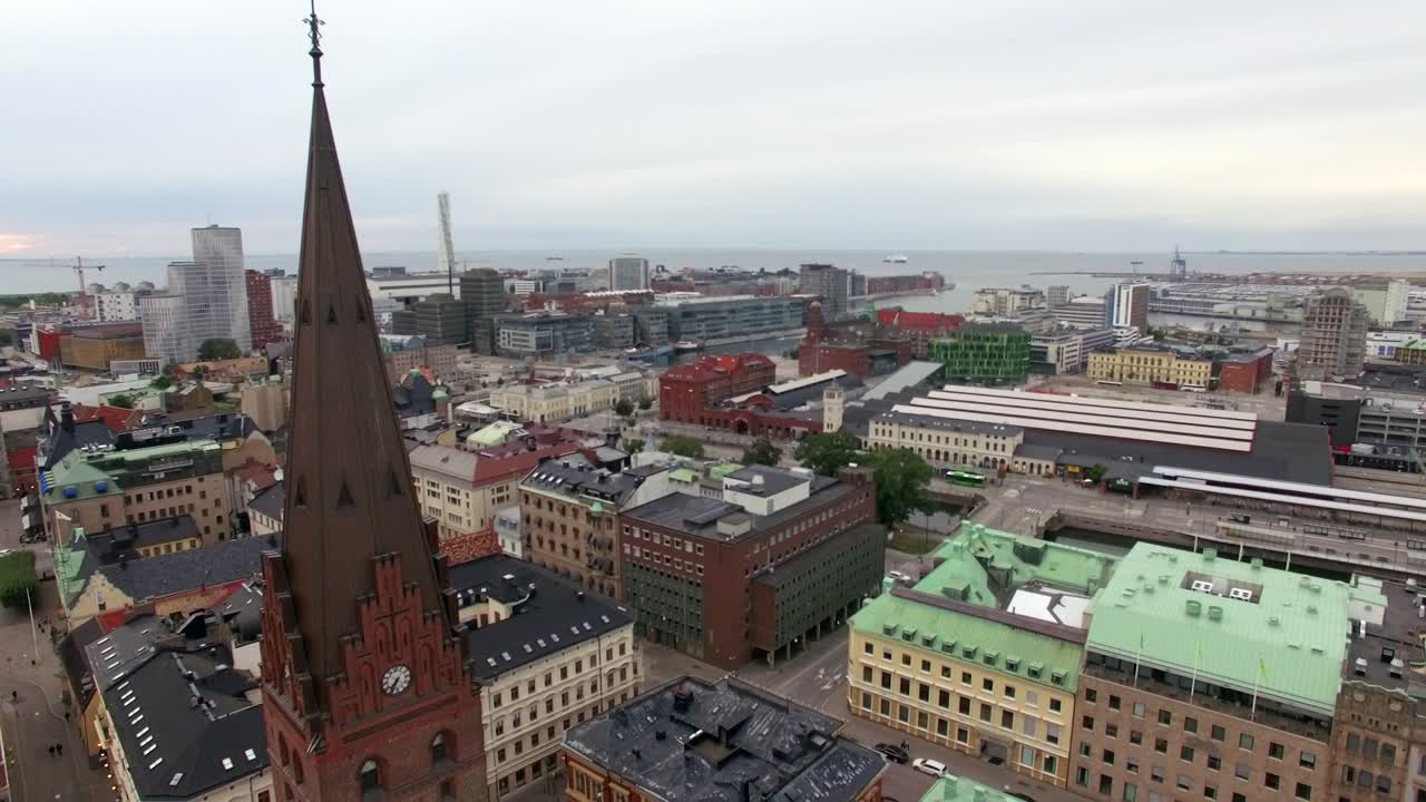 vista aérea de la aguja de la torre de la iglesia, volando hacia abajo frente a la iglesia en la ciudad de malmö. edificios del paisaje urbano en el fondo