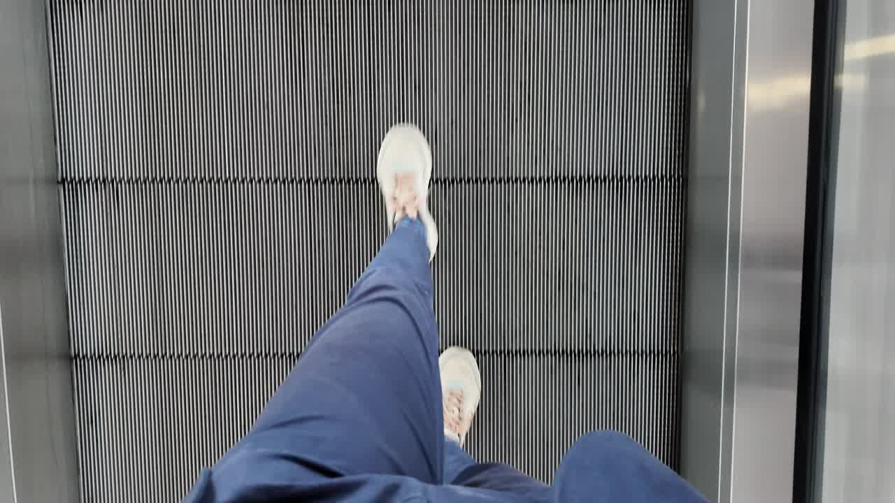 Slow motion of person walking on moving belt at modern airport terminal