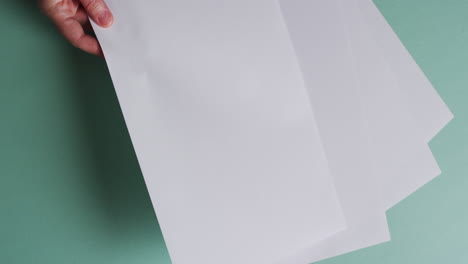 mano sosteniendo un pedazo de papel sobre pedazos de papel con espacio de copia en fondo verde en cámara lenta