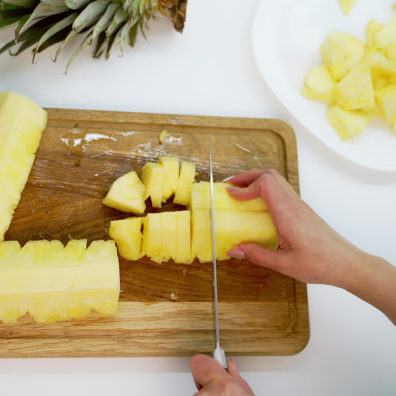 Sliced pieces of pineapple. Peeled pineapple woman cutting into pieces on a wooden board. Tropical food concept.