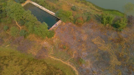 Vista-Aérea-De-Una-Antigua-Piscina-Abandonada-Rodeada-De-Naturaleza-En-India